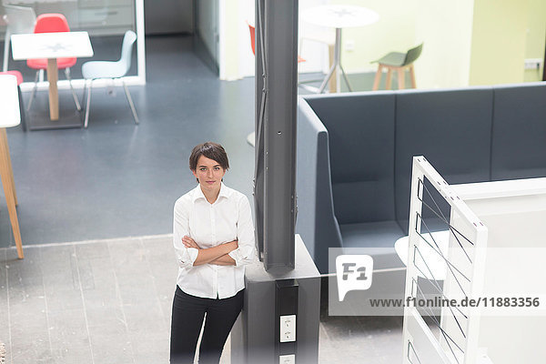 Portrait of young female sales manager in office furniture store  high angle