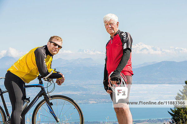 Portrait of senior man and grandson  wearing cycling clothes  standing on hill  Geneva  Switzerland  Europe