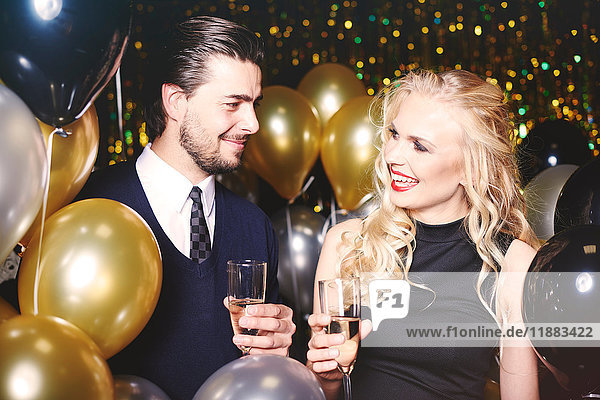 Young man and woman at party  holding champagne glasses  smiling