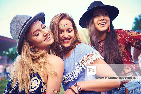 Three young female friends in fedoras dancing at festival