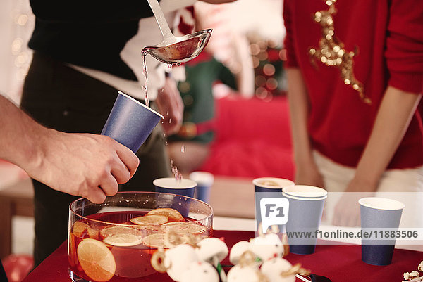 Cropped shot of young man serving punch to friends at christmas party