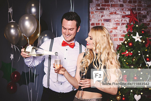 Mann und Frau auf einer Party  Mann gießt Champagner in das Glas der Frau