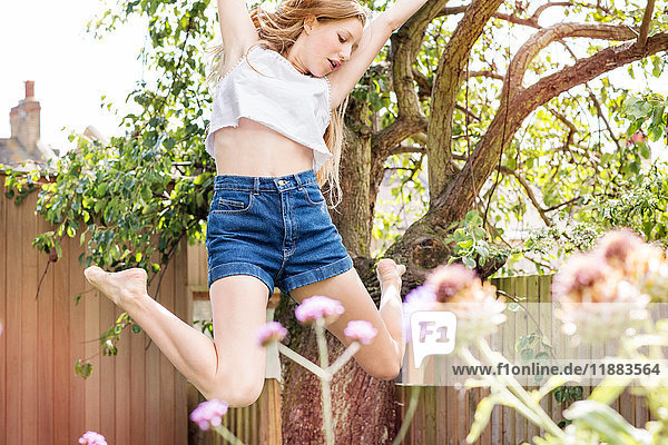 Teenager-Mädchen im Garten springt in die Luft