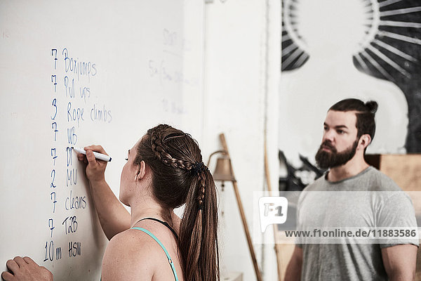 Fitness instructor writing on whiteboard in cross training gym