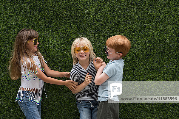 Children in front of artificial turf wall playing tickle