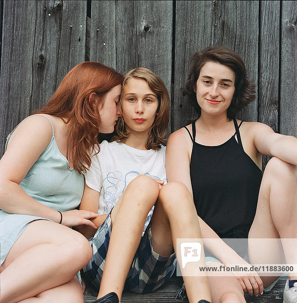 Porträt eines Teenagers  der mit zwei jungen Frauen im Freien sitzt