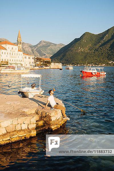 Man sitting on pier in harbor looking away  Perast  Montenegro  Europe