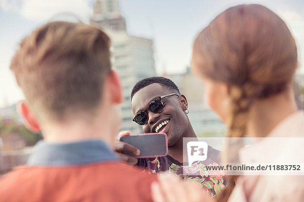 Young man photographing friends at roof party in London  UK