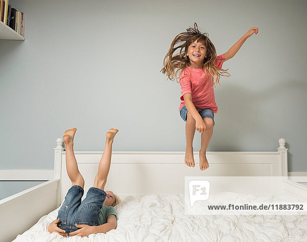Girl in mid air jumping on bed
