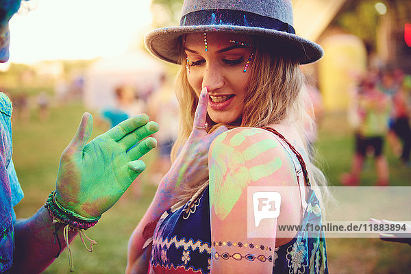 Junge Frau mit grünem Handabdruck auf der Schulter und Freund mit Kreidehand auf dem Festival