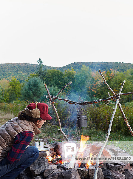 Frau sitzt am Lagerfeuer  kocht Essen  Colgate Lake Wild Forest  Catskill Park  Bundesstaat New York  USA