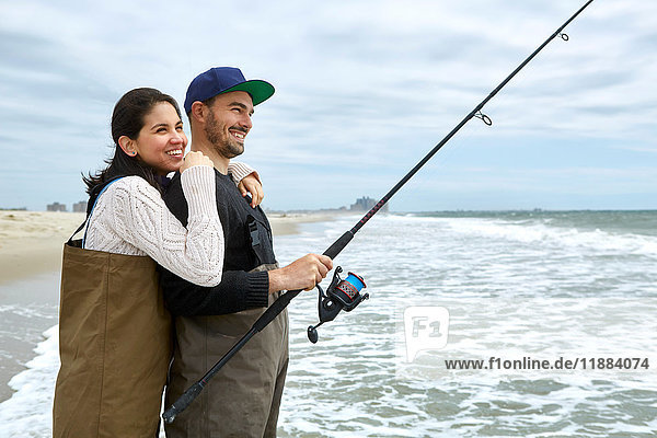 Young couple in waders sea fishing