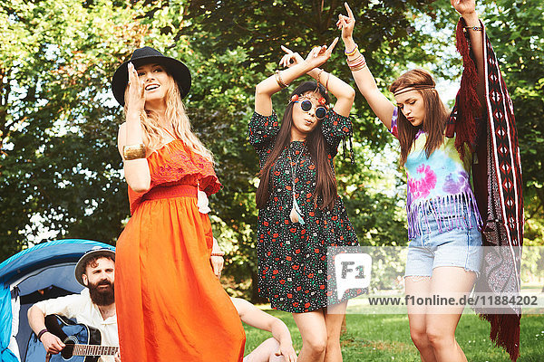 Three young boho women dancing together at festival