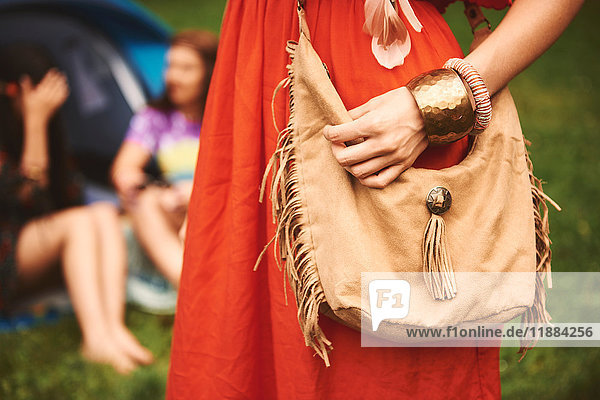 Mittelteil einer Boho-Frau mit geflochtener Umhängetasche beim Festival