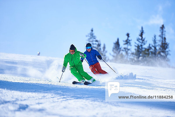 Two men skiing down snow covered ski slope  Aspen  Colorado  USA