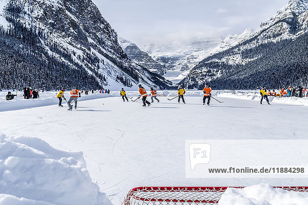 'A pair of hockey teams compete in pond hockey on Lake Louise at the Fairmont Chateau Lake Louise pond hockey tournament in the winter; Lake Louise  Alberta  Canada'