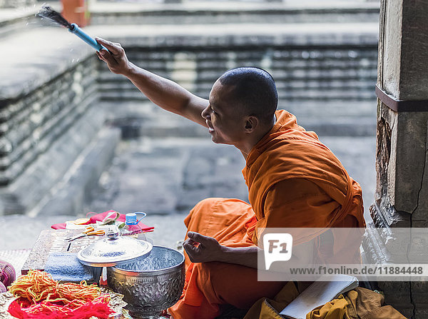 Ein Mönch sitzt in Angkor Wat; Krong Siem Reap  Provinz Siem Reap  Kambodscha'.