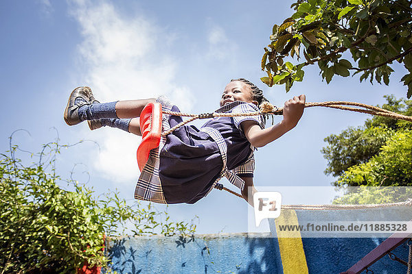 'A young girl swinging on a swing in mid-air; Kampala  Uganda'