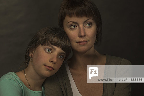 Porträt der nachdenklichen Mutter und Tochter vor grauem Hintergrund