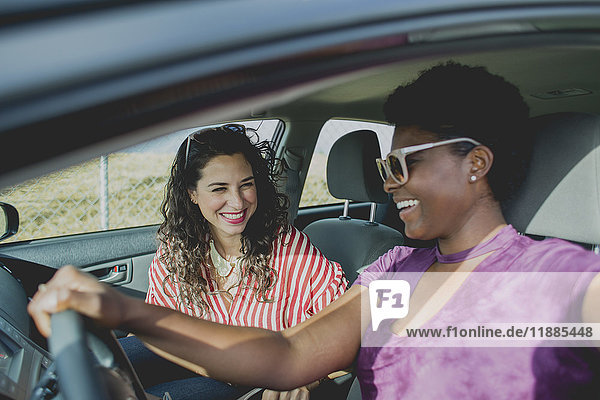 Happy woman looking at young friends driving car