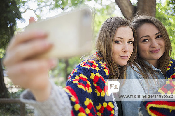 Zärtliche weibliche Freunde  die Selfie durch Smartphone im Park nehmen