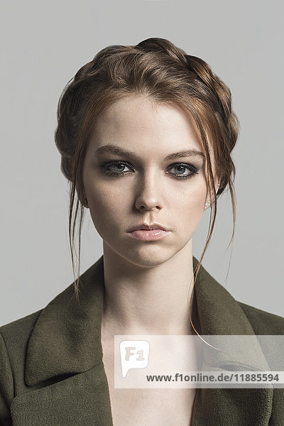 Portrait einer jungen Frau mit Frisur vor grauem Hintergrund