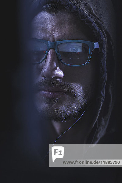 Close-up of serious man wearing eyeglasses and hood