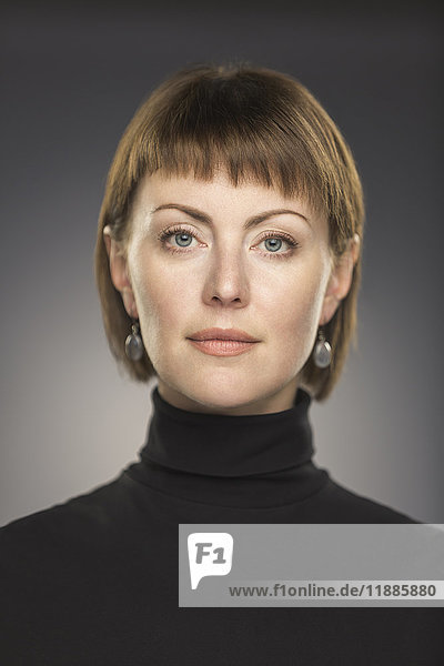 Portrait of mid adult woman with short brown hair against gray background
