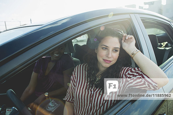 Women looking away while sitting with young female friend in car