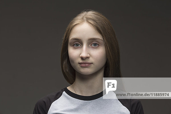 Close-up portrait of teenage girl against gray background