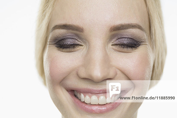Nahaufnahme eines lächelnden Models mit geschlossenen Augen vor weißem Hintergrund