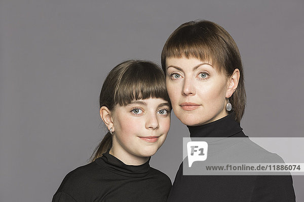Portrait of mother and daughter wearing turtleneck against gray background