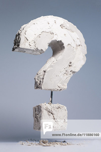 Fragezeichen aus Steinmaterial schwebend auf grauem Hintergrund