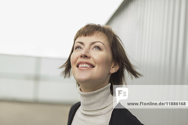 Low angle view of happy mid adult woman looking up against wall
