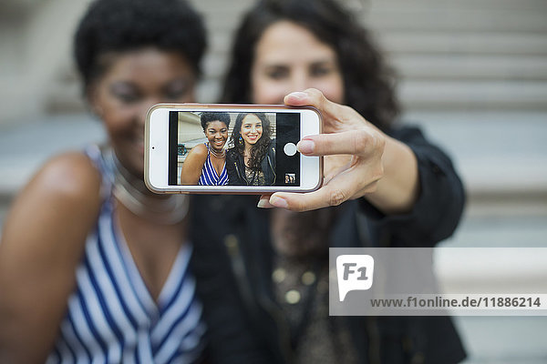 Frau nimmt Selfie mit junger weiblicher Freundin vom Handy