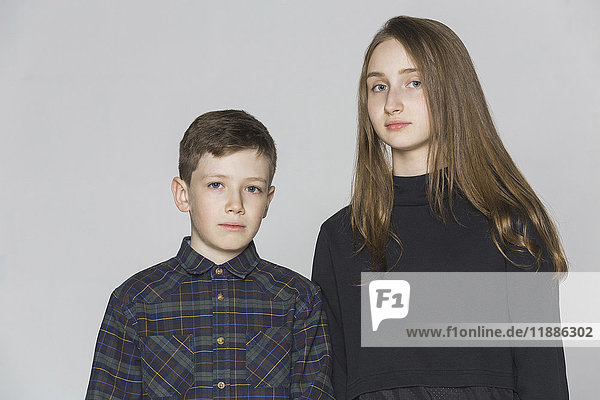 Portrait of siblings standing against white background