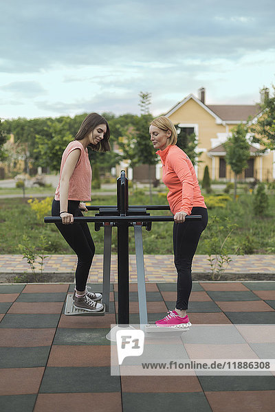 Volle Länge von Mutter und Tochter mit Trainingsgeräten im Park