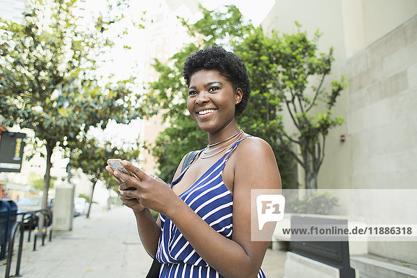 Seitenansicht der lächelnden jungen Frau mit dem Handy in der Stadt