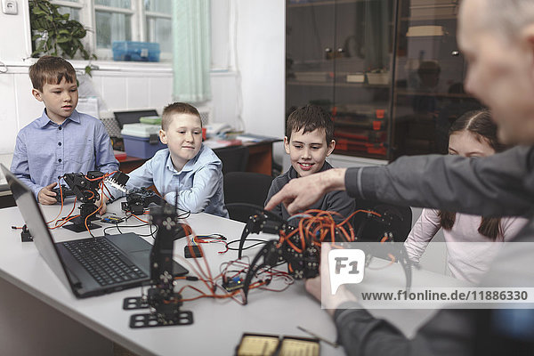 Teacher showing machinery to students sat table in classroom