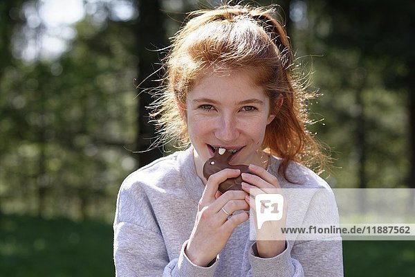 Young girl with chocolate Easter bunny  biting in Easter bunny  Easter  Upper Bavaria  Bavaria  Germany  Europe