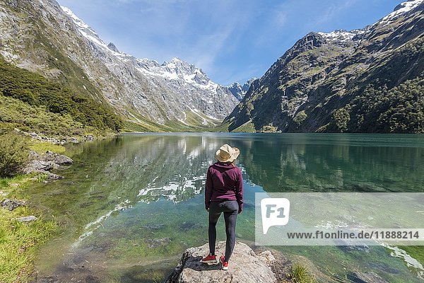Weiblicher Wanderer mit Sonnenhut am Ufer stehend,  Lake Marian,  Fiordland National Park,  Te Anau,  Southland,  Südinsel,  Neuseeland,  Ozeanien