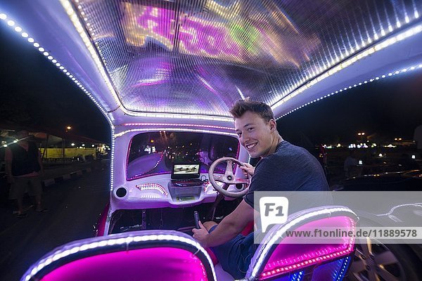 Junger Mann fährt ein buntes  mit LEDs beleuchtetes Auto  Tretauto  Yogyakarta  Java  Indonesien  Asien