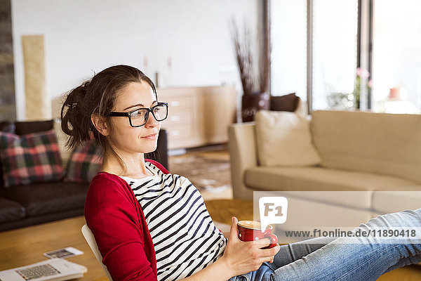 Smiling woman with cup of coffee relaxing at home