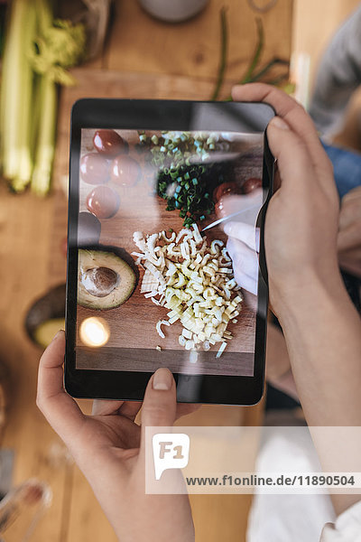 Woman taking picture of prepared vegetables with tablet  close-up