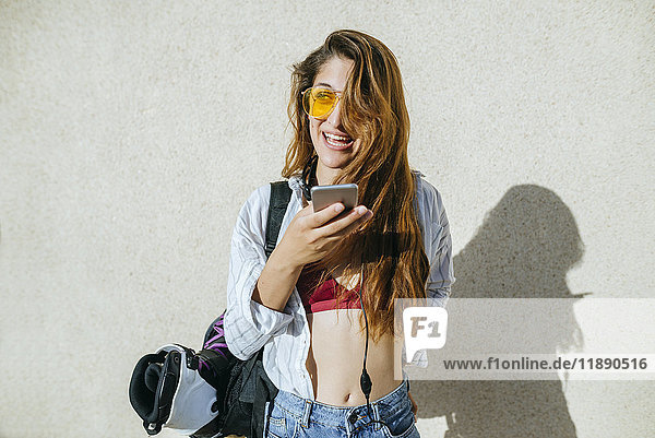 Junge Frau mit Inline-Skates in der Tasche per Handy