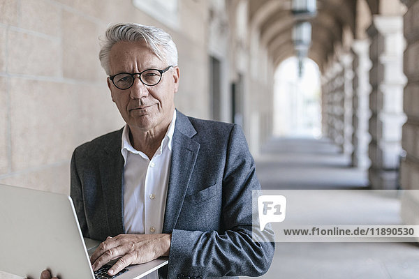 Porträt eines älteren Geschäftsmannes mit Laptop