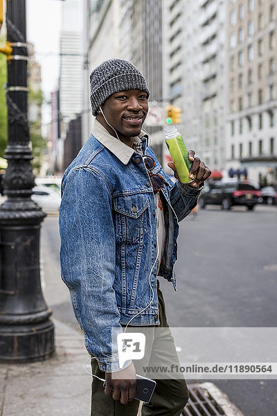 USA  New York City  Manhattan  Portrait eines lächelnden Mannes mit Flasche