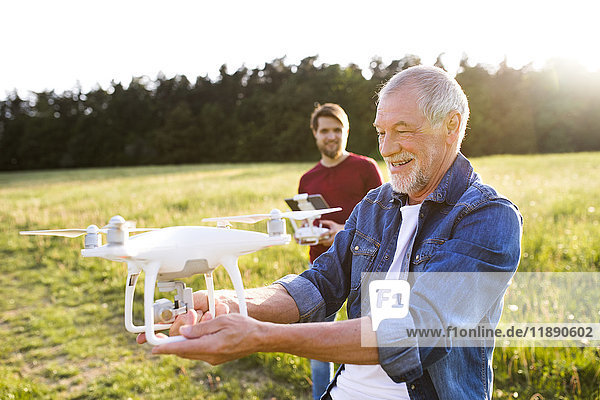 Senior Vater und sein erwachsener Sohn mit Drohne auf einer Wiese