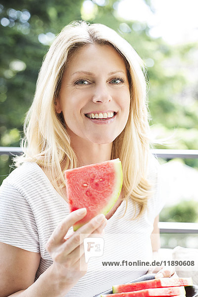 Reife Frau sitzt auf dem Balkon  isst Wassermelone  Porträt