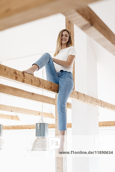 Carefree young woman sitting on ceiling joist